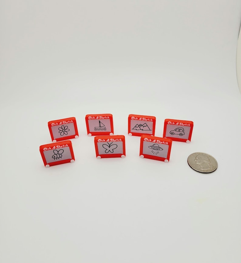 May include: Eight red Etch A Sketch toys with different drawings on the screen. The drawings include a flower, a sailboat, mountains, a car, a butterfly, a bee, and a UFO.
