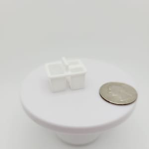 May include: White plastic double sink dish drying rack with a handle. The rack is about the size of a US quarter.