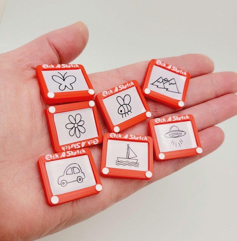 May include: Eight red Etch A Sketch toys with different drawings on the screen. The drawings include a butterfly, mountains, a bee, a flower, a sailboat, a UFO, and a car.