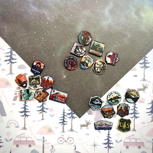 May include: A collection of small, multi-shaped patches featuring colorful illustrations of various United States national parks, including Arches, Grand Canyon, Olympic, Zion, and Lake Tahoe, with text labels identifying each specific location.