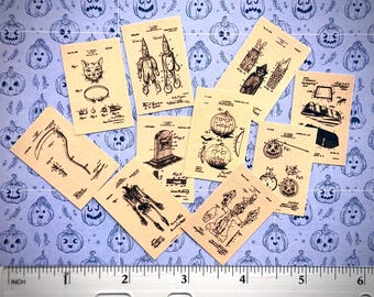 May include: A collection of ten rectangular paper cards featuring black ink illustrations of vintage Halloween patent designs, including a skeleton, jack-o'-lanterns, a tombstone, and a scythe, positioned above a ruler showing 6 inches in length.