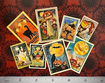 May include: A collection of eight rectangular Halloween-themed paper cards featuring vintage illustrations of pumpkins, black cats, ghosts, and a moon, arranged above a clear plastic ruler showing a scale of up to 6 inches in length.