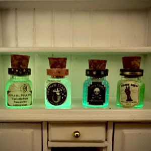 May include: Four glowing potion bottles with cork stoppers are displayed on a white shelf. Each bottle has a unique label and contains a different colored, glittery liquid. The labels read "Snail Malice", "Mermaid Tears", "Poison", and "Zombie Brew".