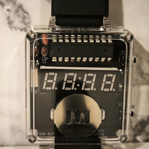 K&ouml;nnte beinhalten: Eine transparente, quadratische Digitaluhr mit schwarzem Zifferblatt, das die Zeit "8:8:8:8" anzeigt. Die Uhr hat ein schwarzes Armband und sichtbare interne Komponenten. Das Uhrengeh&auml;use ist transparent und gibt den Blick auf die Platine und andere elektronische Elemente frei.