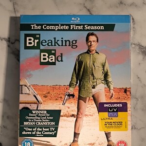 Peut inclure: Boîtier Blu-ray de la première saison de la série télévisée Breaking Bad. Le boîtier présente une photo de Bryan Cranston dans le rôle de Walter White, le personnage principal, dans un décor désertique. Le texte "Breaking Bad" est imprimé en blanc sur fond noir. Le boîtier comprend également le texte "The Complete First Season" et "Winner Emmy Award for Outstanding Lead Actor in a Drama Series - Bryan Cranston".
