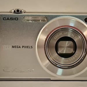May include: A silver Casio Exilim digital camera with a 10.1 megapixel resolution and a lens with a 7.9-72mm focal length and a 1:2.8-5.1 aperture.