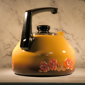 Peut inclure: Une bouilloire en émail jaune avec une poignée noire et un motif floral. La bouilloire a un dégradé brun en bas et présente des fleurs orange.