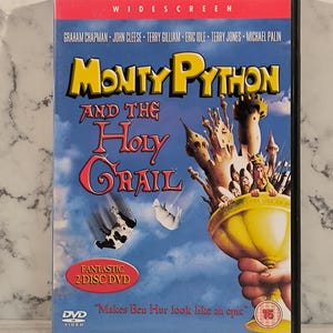 Puede incluir: Una caja de DVD para la película Monty Python y el Santo Grial. La caja es negra con una imagen roja y amarilla del título de la película y una escena de la película. La caja también incluye el texto "Fantastic 2-Disc DVD" y "Makes Ben Hur look like an epic."