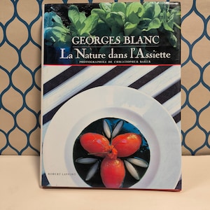 May include: A book titled "La Nature dans L'Assiette" by Georges Blanc with a photograph of a red tomato sorbet on a white plate with a black background.