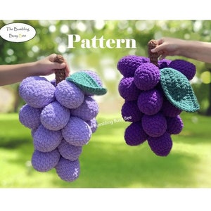Pode incluir: Dois cachos de uvas de crochê, um roxo e outro roxo claro, com folhas verdes. As uvas são feitas com um fio texturizado e têm uma aparência realista. O padrão é chamado "The Bumbling Busy Bee".