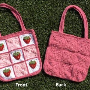 May include: A pink crocheted tote bag with a strawberry pattern on the front. The back of the bag is plain pink.