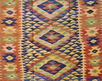May include: A vintage rug with a geometric pattern in shades of red, orange, yellow, blue, and green. The rug has a traditional design with repeating diamond shapes and intricate details.