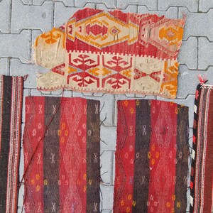 May include: Five vintage Turkish rugs with geometric patterns in red, black, and white. The rugs are made of wool and have a hand-woven texture.