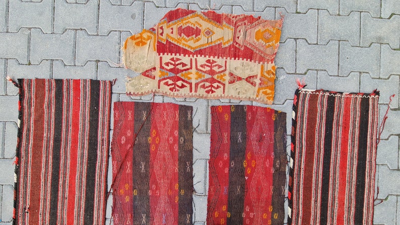 May include: Five vintage Turkish rugs with geometric patterns in red, black, and white. The rugs are made of wool and have a hand-woven texture.