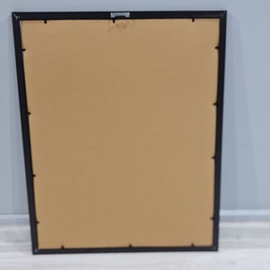 May include: A black picture frame with a brown mat. The frame is empty.