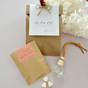 Peut inclure: Un coffret cadeau avec un sac en papier brun et une carte blanche avec les mots "merci" et "Pour cette belle année". Comprend un petit paquet, des fondants parfumés en forme de cœur et un désodorisant pour voiture.