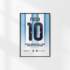 Pode incluir: Um cartaz vertical emoldurado com um fundo de listras azul-claras e brancas. O texto MESSI e o número 10 são exibidos em uma fonte grande azul-escura. Abaixo, o texto diz MESSI BREAKS ALL TIME WORLD CUP RECORD, com detalhes da partida incluindo Argentina 2-0 Áustria e a data 22 de junho de 2026.