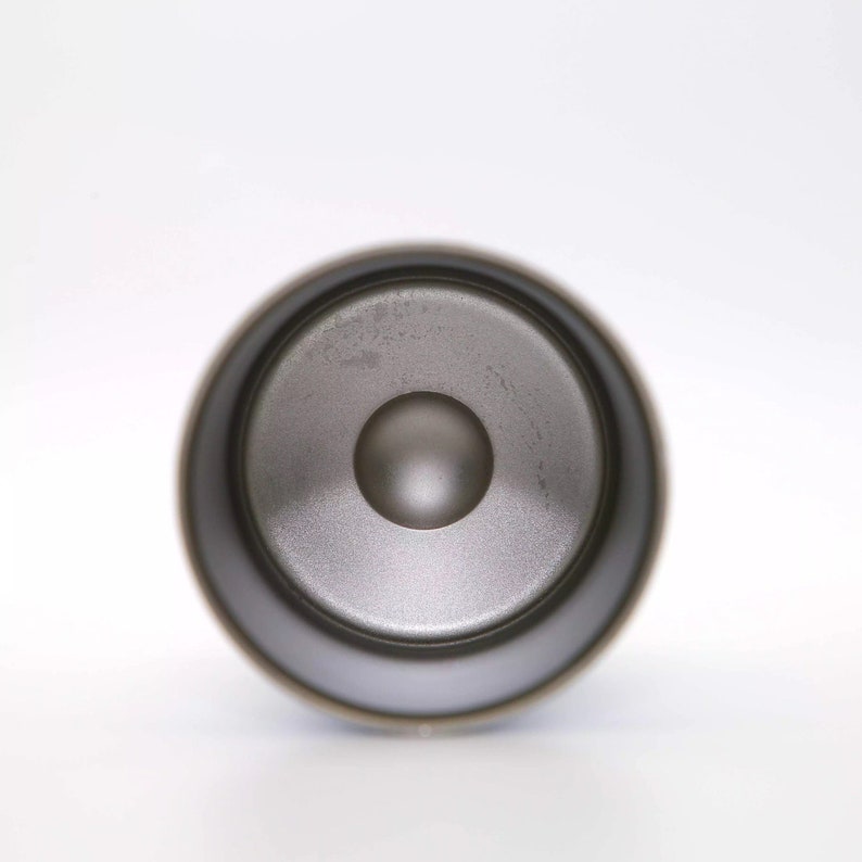 May include: A close-up of a black speaker with a round, silver speaker cone.