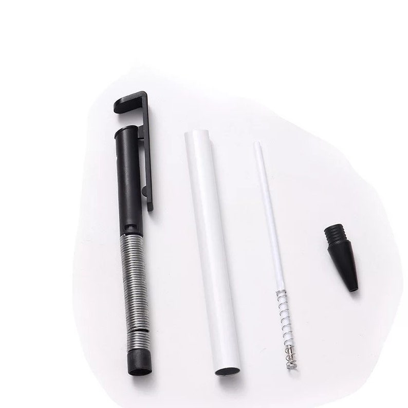 May include: Disassembled black and silver pen with a clip, a white barrel, a white rod with a spring, and a black tip. The pen components are arranged on a white background, showcasing the internal parts of the writing instrument.