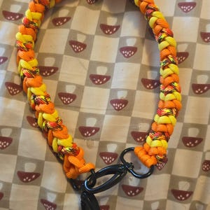 May include: A braided orange and yellow lanyard with black metal clips.