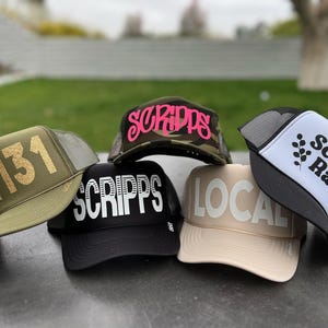 May include: Five different trucker hats with various designs and colors. The hats feature the text "Scripps Ranch", "Scripps", "Local", "92131", and "Scripps" in different fonts and colors.