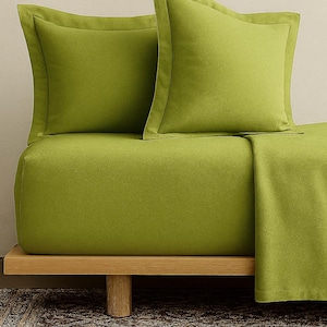 May include: A lime green bed set with two matching pillowcases. The bedding is neatly arranged on a wooden bed frame. The pillowcases have a contrasting border. The overall aesthetic is modern and minimalist.