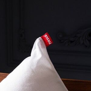 May include: White pillow with a red label that says "nesco" on it.