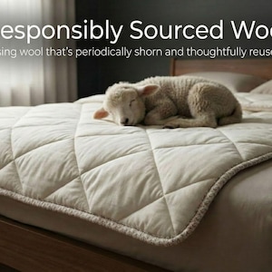 May include: A cream-colored, quilted mattress cover with a sleeping lamb. The cover is on a wooden bed frame. The text at the top reads "Responsibly Sourced Wool". The cover has a diamond pattern and a decorative border.