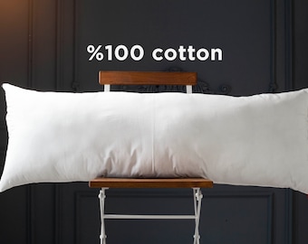 May include: A white, rectangular pillow made of 100% cotton, resting on a wooden chair with a white metal frame. The pillow is positioned horizontally on the chair, with the text "%100 cotton" displayed above it.