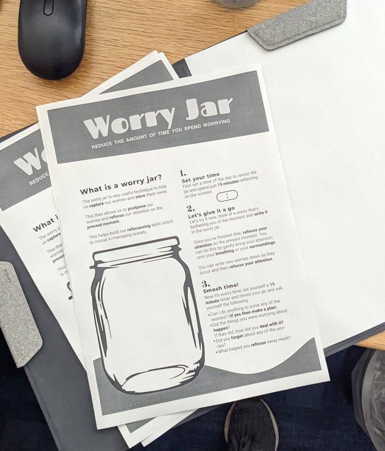 May include: A black and white illustration of a glass jar with a lid. The text "Worry Jar" is at the top of the page. The text "Reduce the amount of time you spend worrying" is below the title. The page has instructions on how to use a worry jar to reduce anxiety.