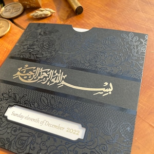 May include: A black and gold wedding invitation with a floral design and the text "Sunday eleventh of December 2022".