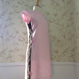 May include: A pink sleeveless dress with a brown and white floral design on the side.
