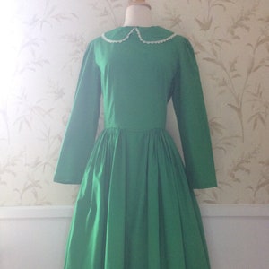 May include: A green vintage dress with a white lace collar and a colorful animal print design around the hem.