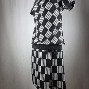 May include: A black and white checkered dress with short sleeves. The dress features a geometric pattern of alternating black squares and white vertical stripes. A black belt cinches the waist, and a bow detail is on the skirt.