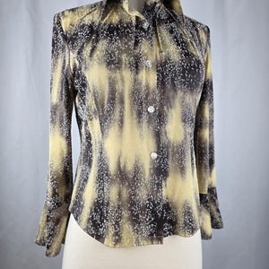 May include: A button-down shirt with a unique pattern of yellow, brown, and white. The long-sleeved shirt has a collared neckline and is displayed on a mannequin. The fabric has a textured appearance.