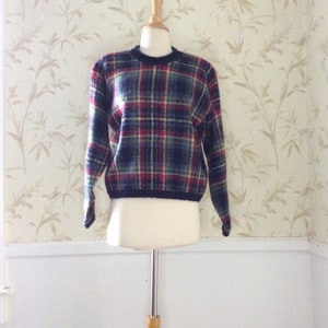 May include: A blue, red, and green plaid sweater with a crew neck.