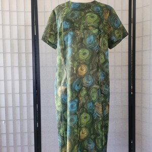 May include: A vintage green, blue, and gold dress with a swirling abstract pattern. The dress has short sleeves and a round neckline.
