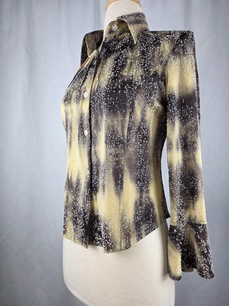 May include: A long-sleeve button-down shirt with a unique pattern. The shirt features a blend of brown and yellow hues with a speckled design. The collar and cuffs are visible, and the shirt is displayed on a mannequin.