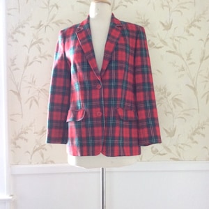 May include: A red and green plaid blazer with a single button closure. The blazer is on a white mannequin and has a white background.