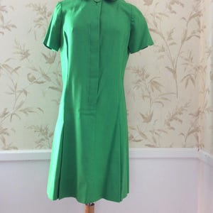 May include: A bright green vintage dress with a collared neckline and short sleeves. The dress has a button-up front and a slightly flared skirt.