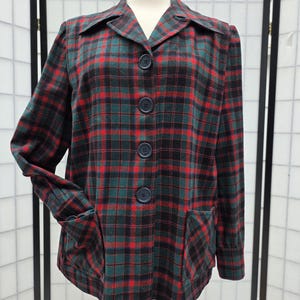May include: A vintage plaid jacket in a classic pattern of red, green, and black. The jacket features a collared neckline, four dark buttons, and two front pockets. The jacket is displayed on a mannequin.