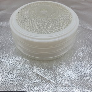 May include: A white glass ceiling light fixture with a textured glass shade. The shade has a circular pattern of small raised dots.