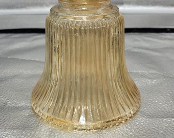 May include: A clear, amber-colored glass lampshade with vertical ribbed detailing. The shade has a flared, bell-like shape and a slightly textured surface. The top has a smaller opening, and the overall design is vintage.