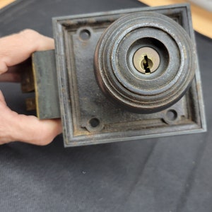 May include: A vintage brass door knob with a keyhole and a square-shaped plate. The knob has a circular design with concentric rings.