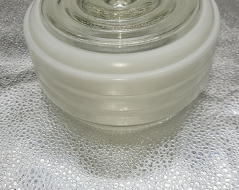 May include: A white glass ceiling light fixture with a layered design. The fixture has a clear glass center and a white frosted outer layer.