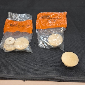 May include: Two clear plastic bags containing wooden cabinet knobs and screws. One bag contains several knobs and the other contains knobs and screws. A single wooden knob is also visible.