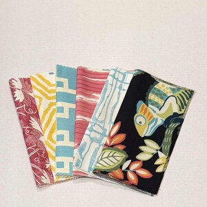 May include: A collection of six fabric swatches with various patterns and colors. The swatches include a red floral pattern, a yellow geometric pattern, a blue geometric pattern, a pink striped pattern, a blue and white geometric pattern, and a black fabric with a green and orange floral pattern.