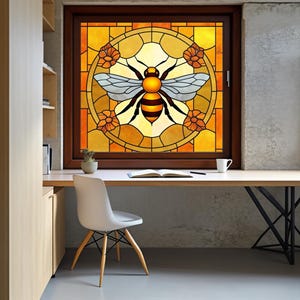 Könnte beinhalten: Ein Buntglasfenster mit einem Bienenmotiv. Die Biene hat einen gelb-schwarzen Körper mit hellblauen Flügeln, eingebettet in ein kreisförmiges Design mit orangefarbenen Blumen. Das Fenster ist in einem dunkelbraunen Holzrahmen gefasst.