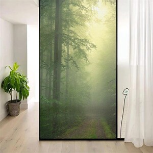 May include: A window film with a misty forest scene. The image shows a path leading into a dense forest with tall trees and a soft, green glow.