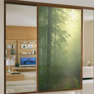 May include: A sliding glass door with a printed image of a misty forest path. The door is framed in wood and has a frosted glass panel on the left side.